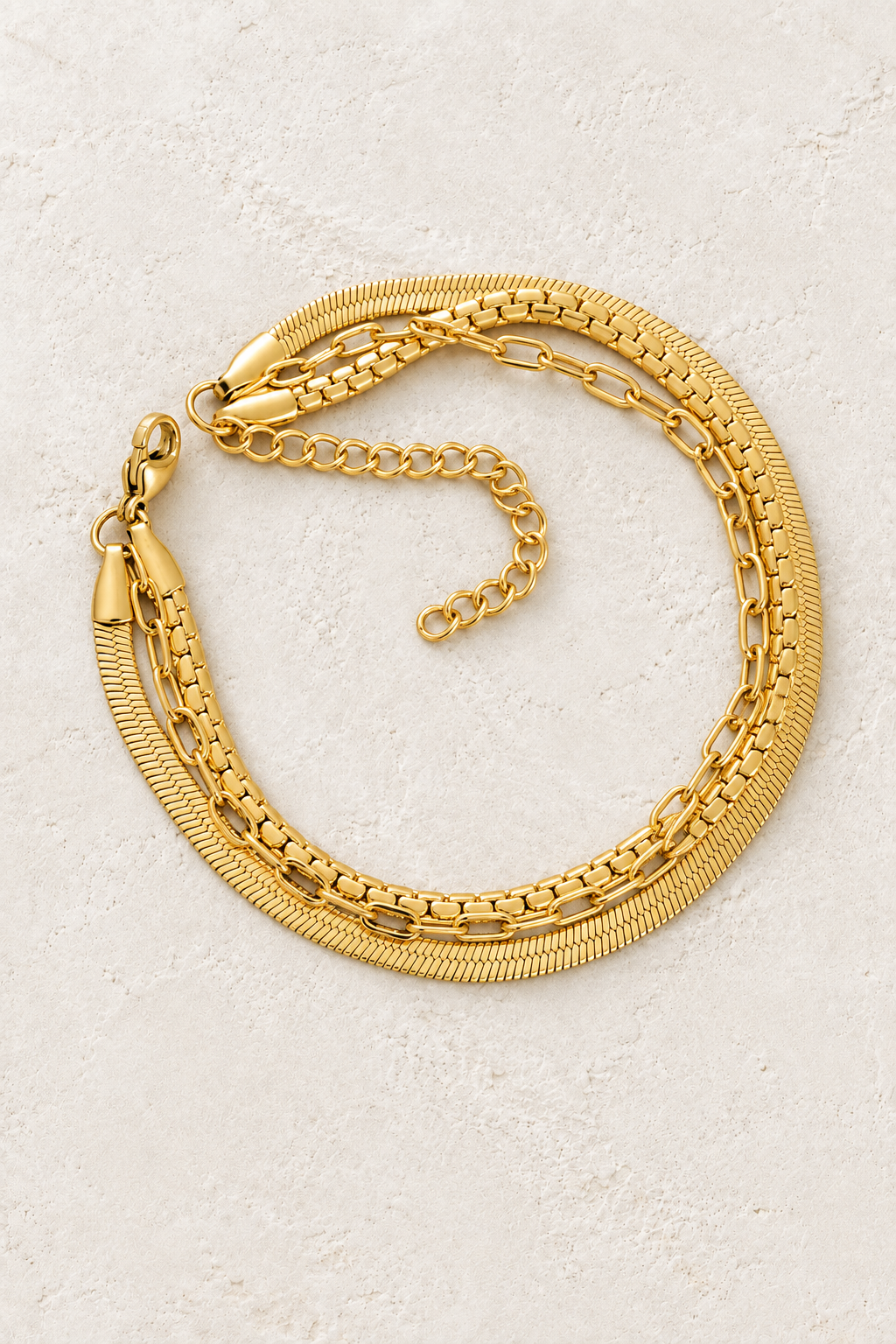 
                  
                    Gold Triple Chain Bracelet on ivory stone
                  
                