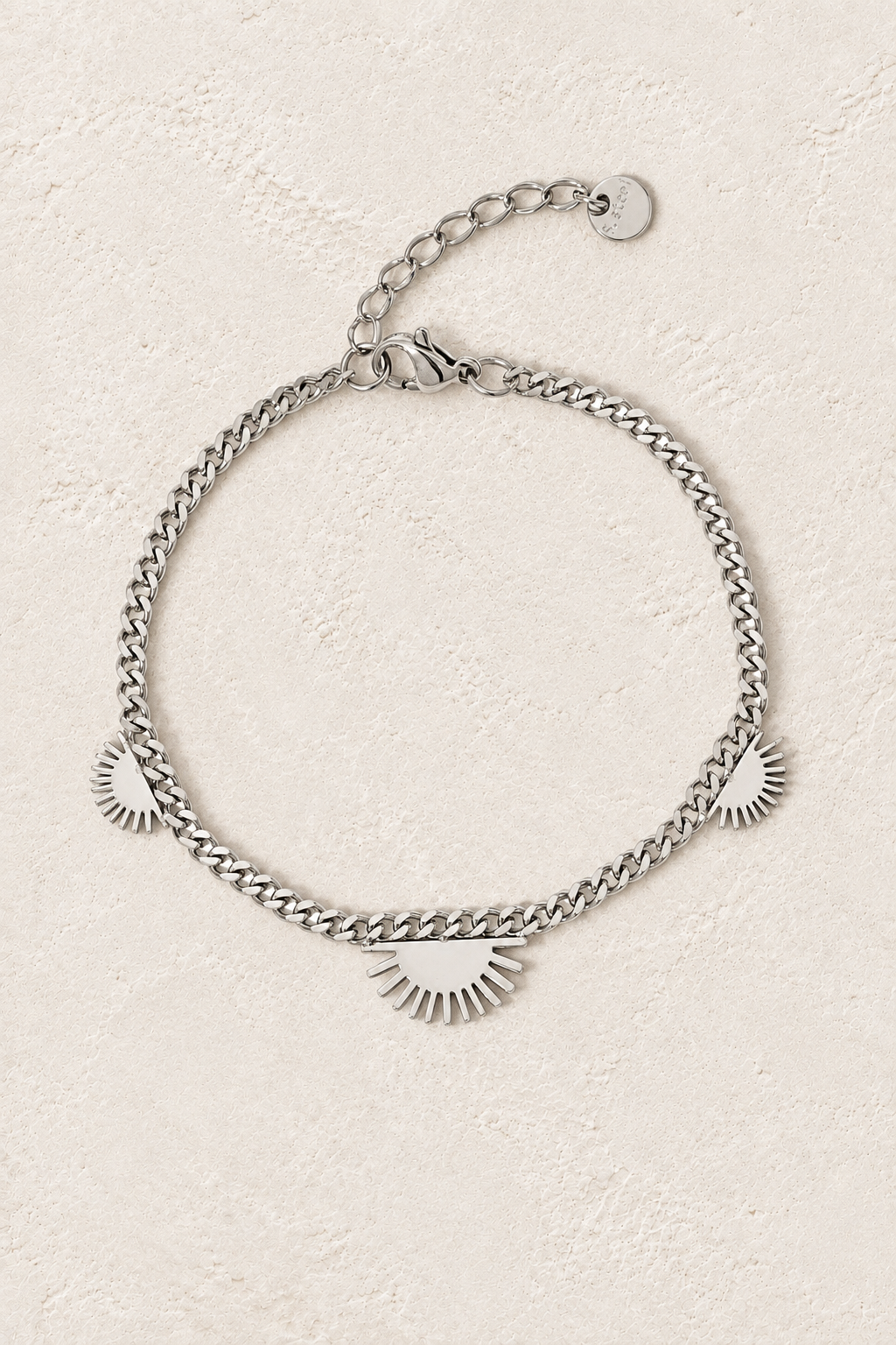 
                  
                    Silver Sunburst Charm Chain Bracelet on ivory textured background
                  
                