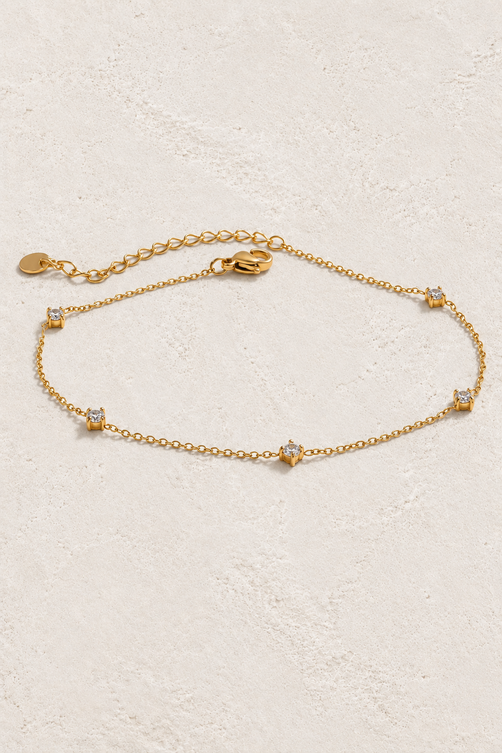 Dainty Crystal Drop Gold Bracelet on ivory textured background