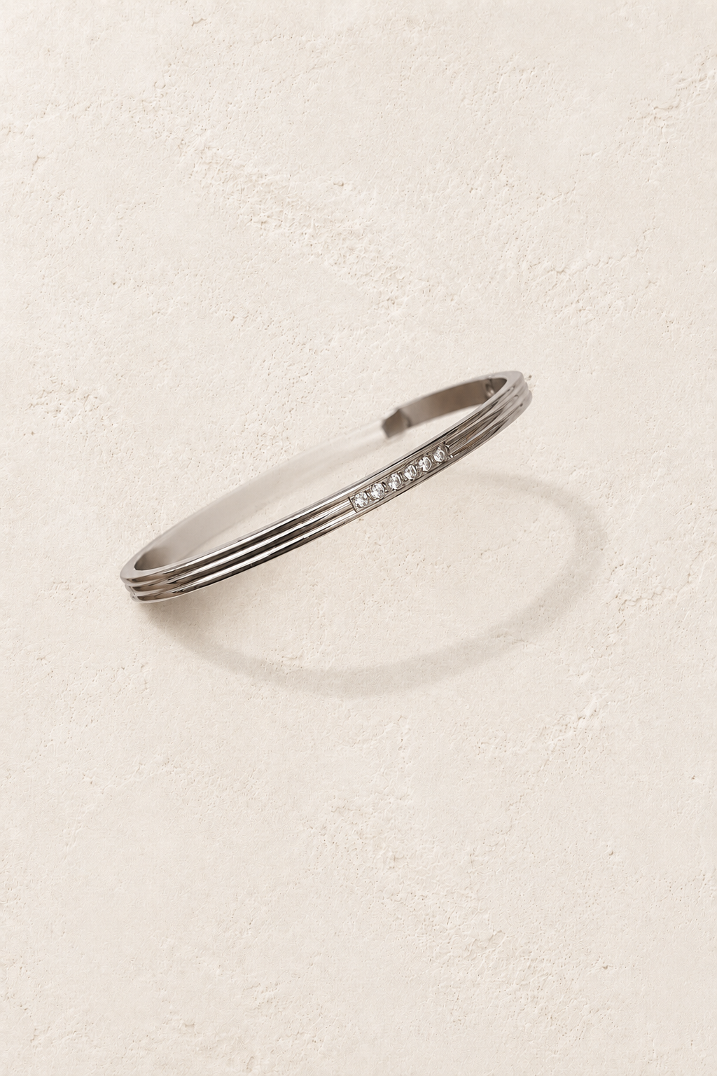 Elira Silver Triple Line Crystal Bangle on cream beige textured background