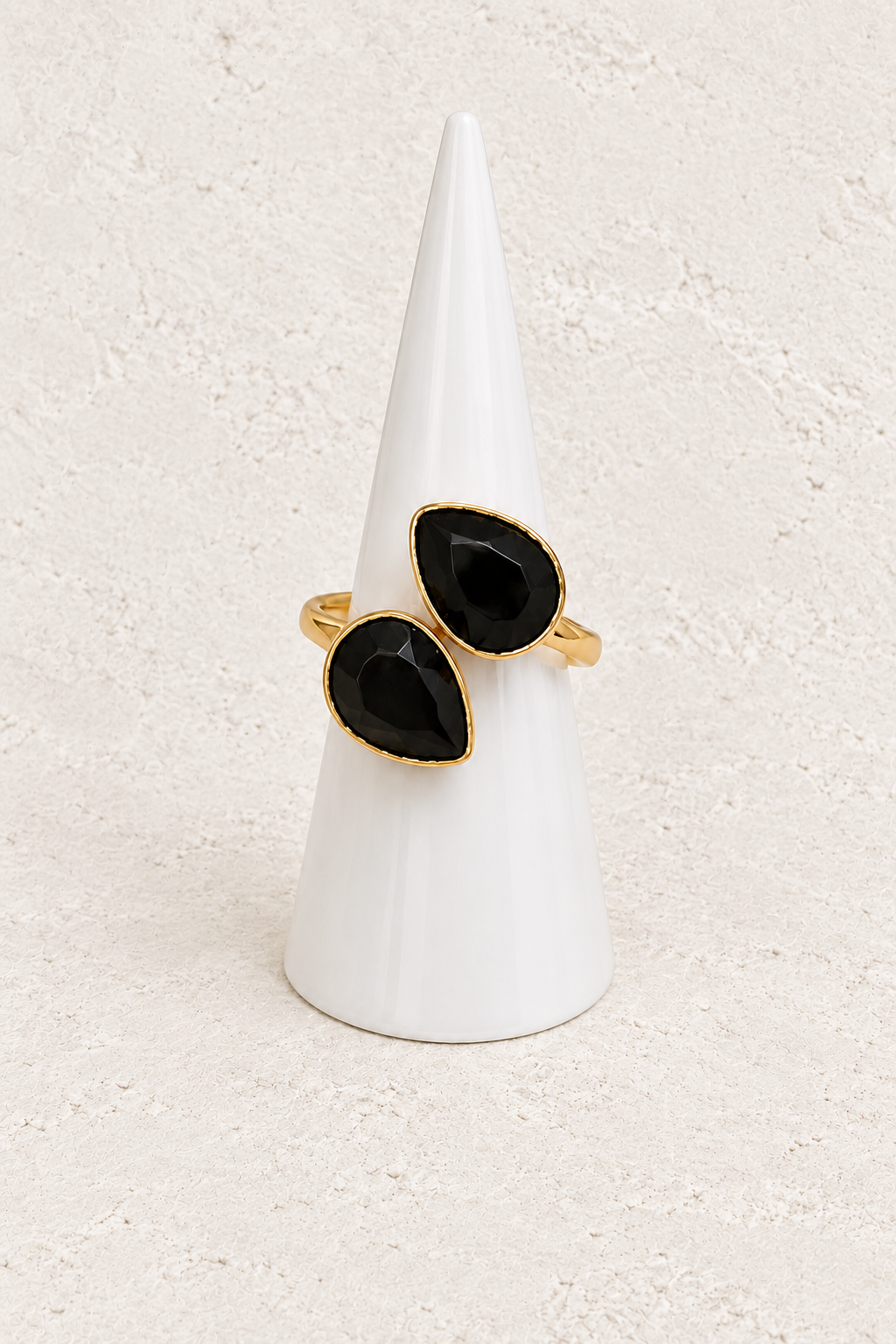 Esme Black Obsidian Adjustable Ring on white cone against warm textured background