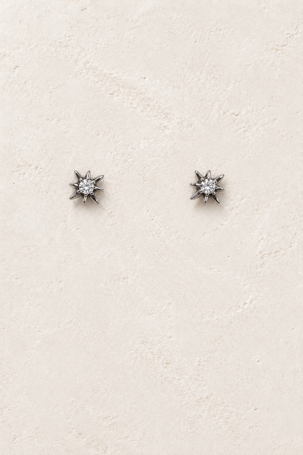 
                  
                    Estelle Silver Starburst Stud Earrings on warm ivory plaster
                  
                