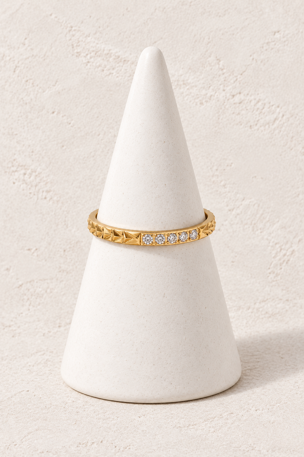 Estelle Star Crystal Ring on a white display cone against a warm textured background