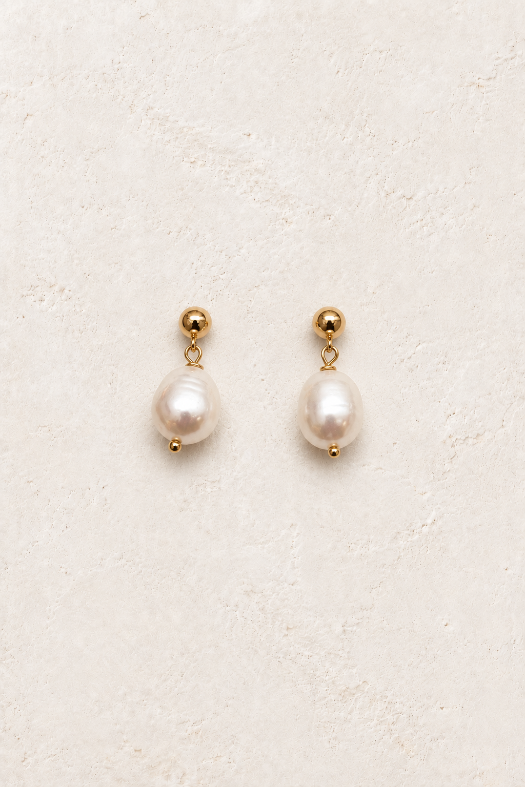 
                  
                    Evara Pearl Drop Studs on warm ivory textured background
                  
                