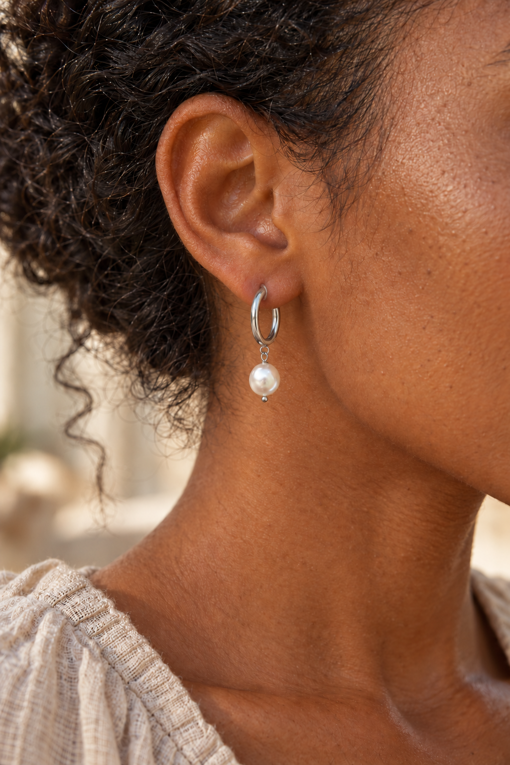 Florina silver pearl hoop earring sitting naturally through a model's ear piercing