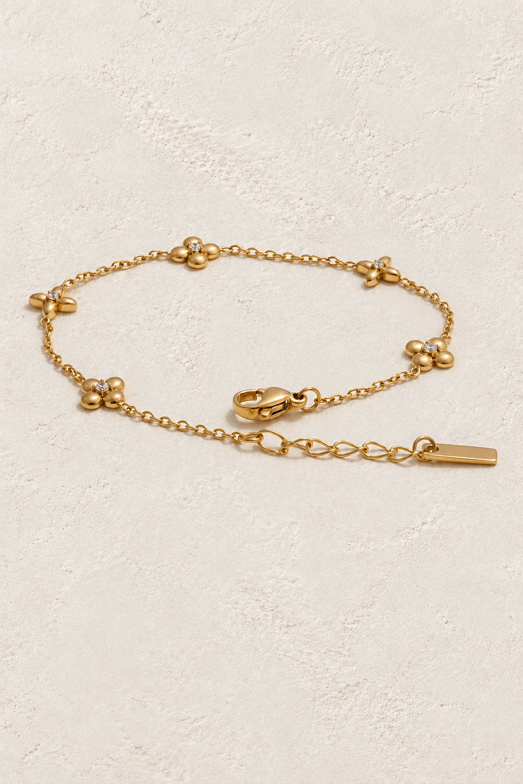 Four-Petal Crystal Flower Chain Bracelet – Gold on approved cream hero background