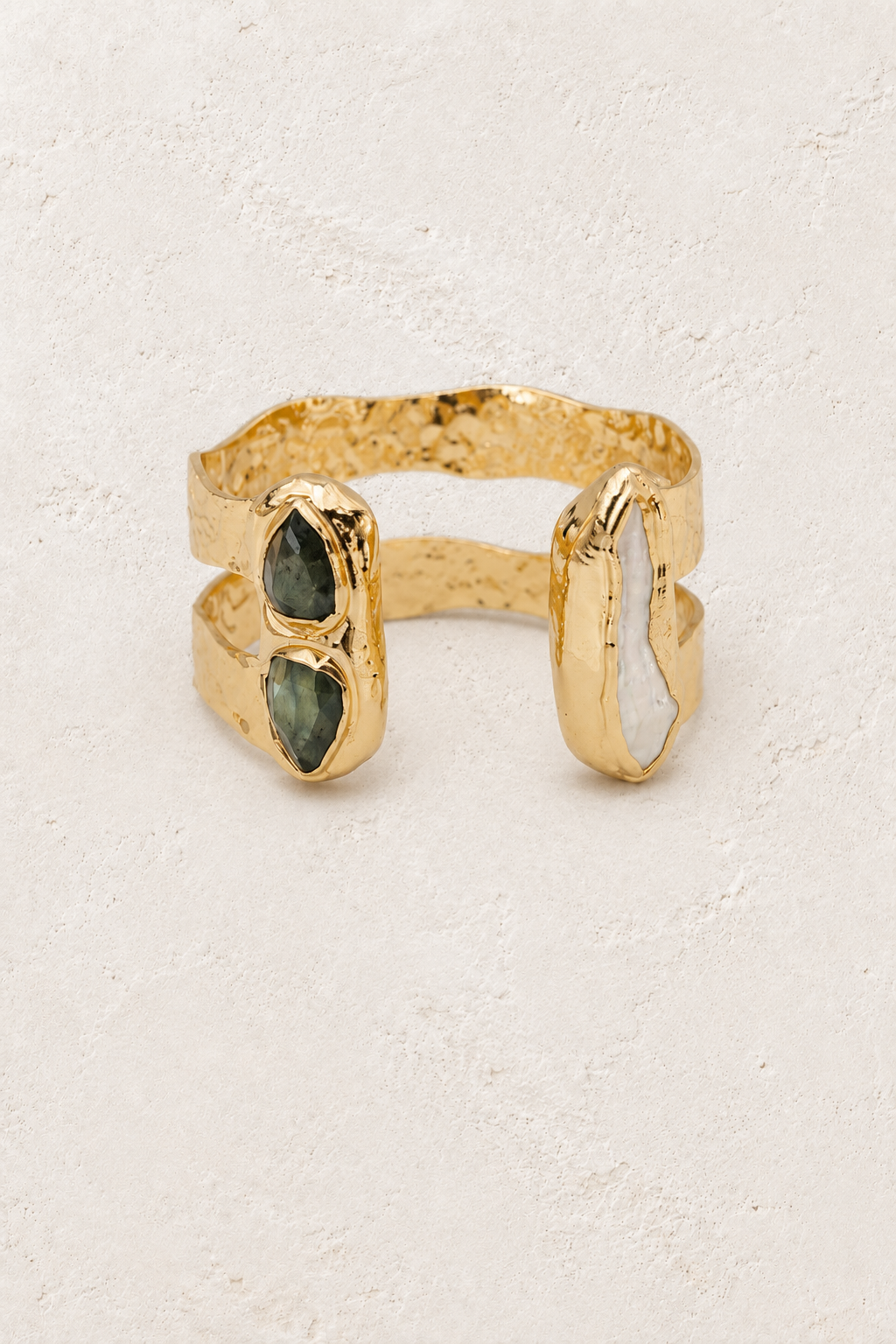 Free Spirit gold cuff with labradorite and freshwater pearl on a warm off-white textured plaster background