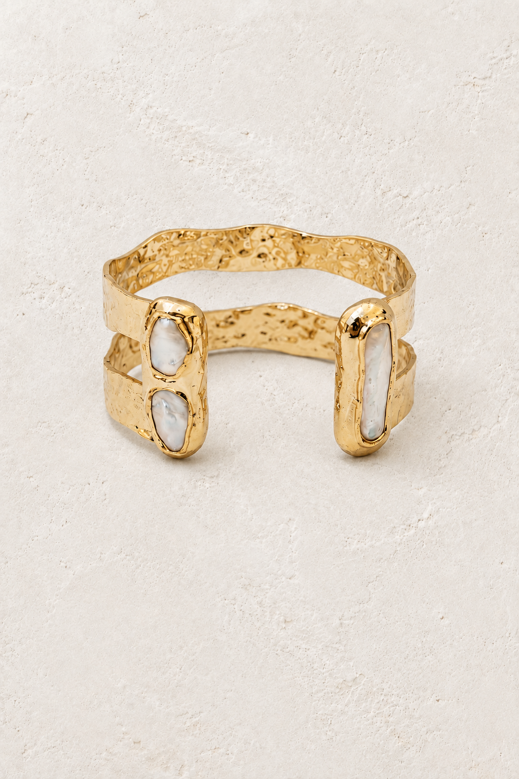 Free Spirit gold cuff with three freshwater pearls on a warm off-white textured plaster background