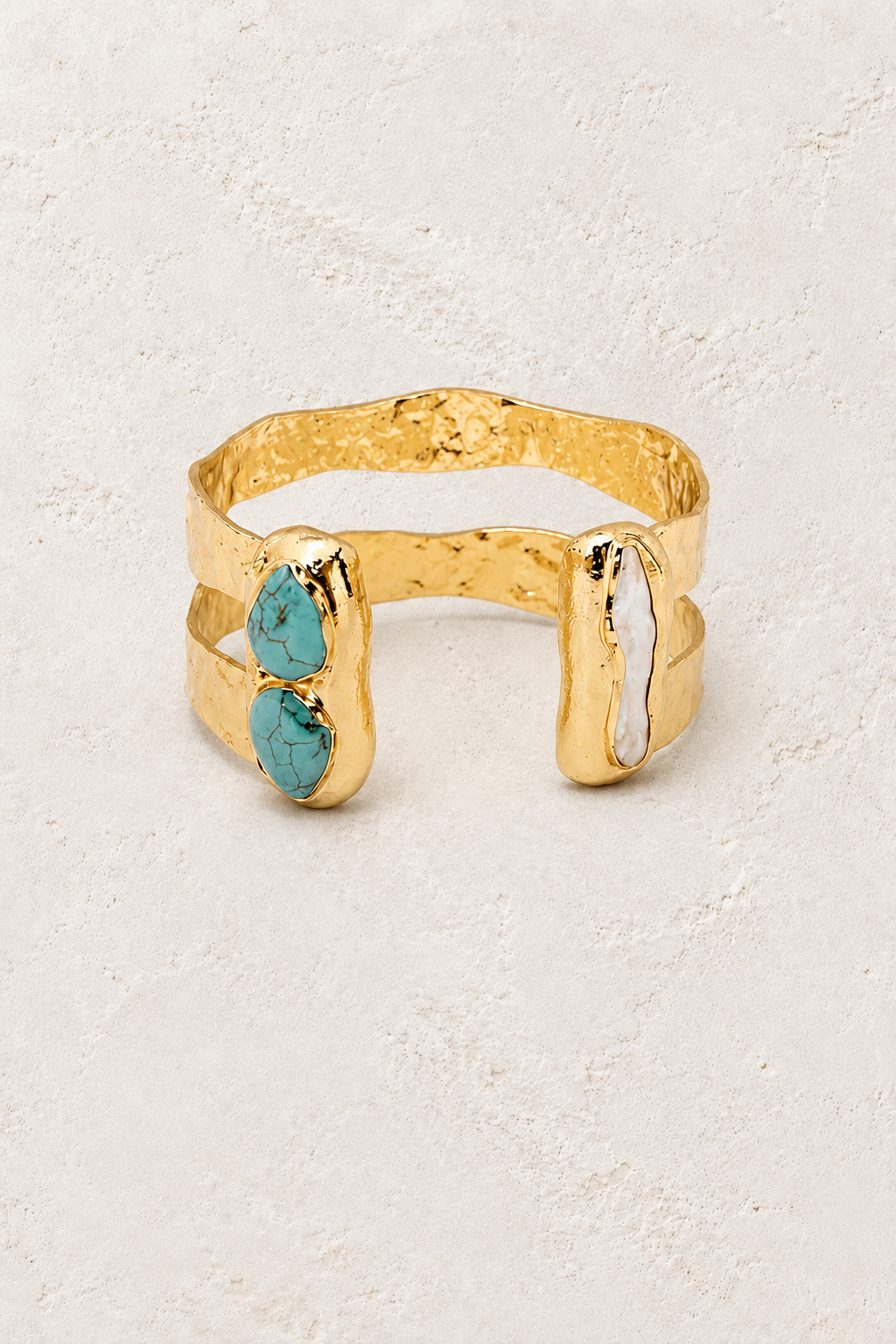 
                  
                    Free Spirit gold cuff with turquoise and freshwater pearl on a warm off-white textured plaster background
                  
                