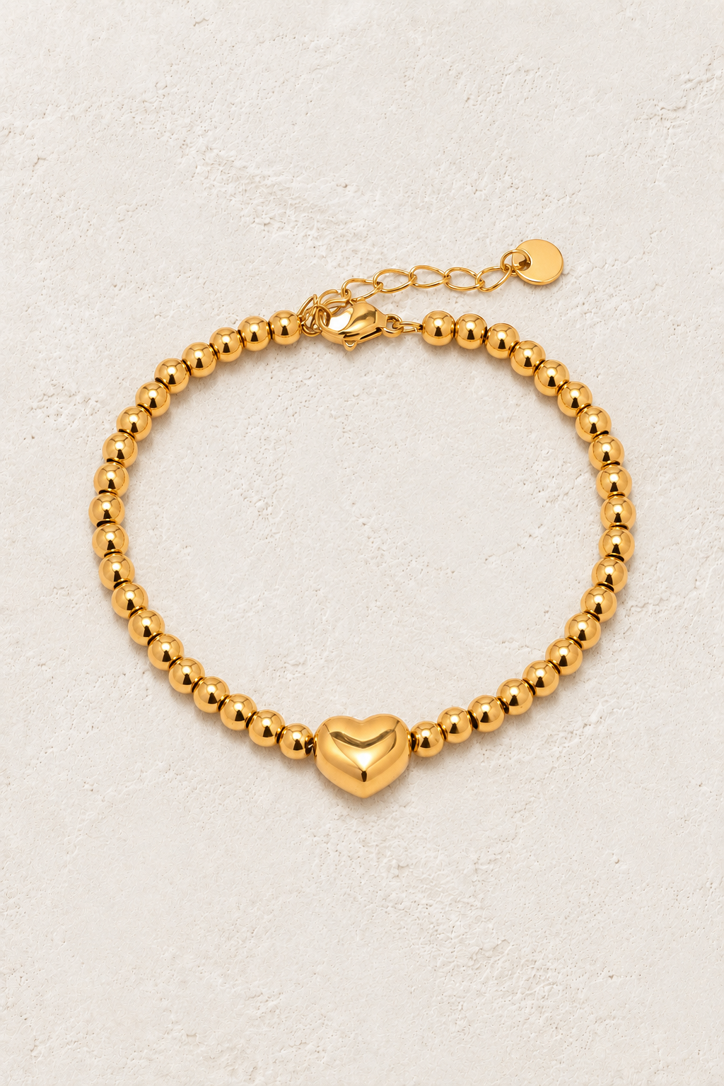 
                  
                    Gold Bead Heart Bracelet on ivory textured background
                  
                