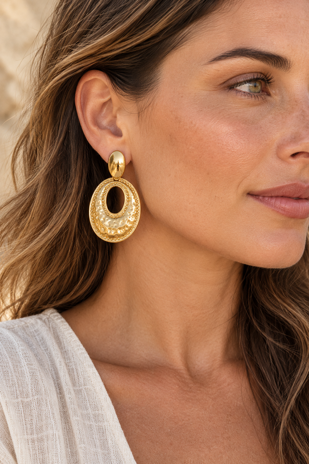 
                  
                    Gold hammered oval 61mm drop earrings worn on model
                  
                