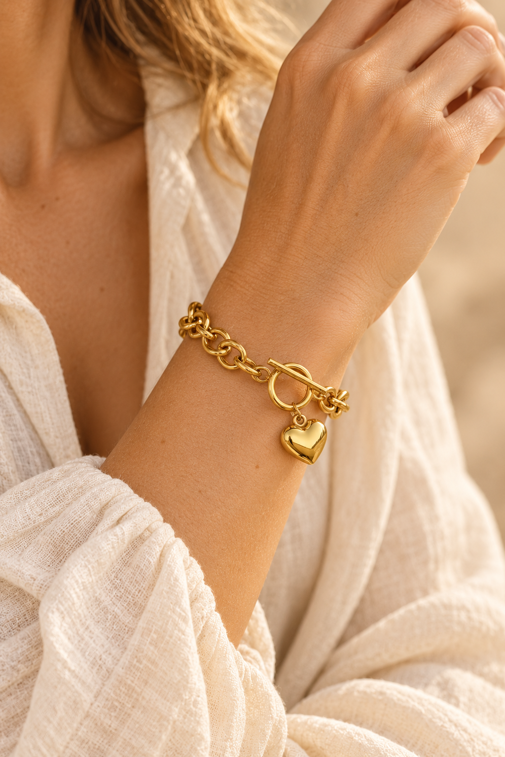 
                  
                    Gold heart toggle bracelet with oval links worn on a model's wrist
                  
                
