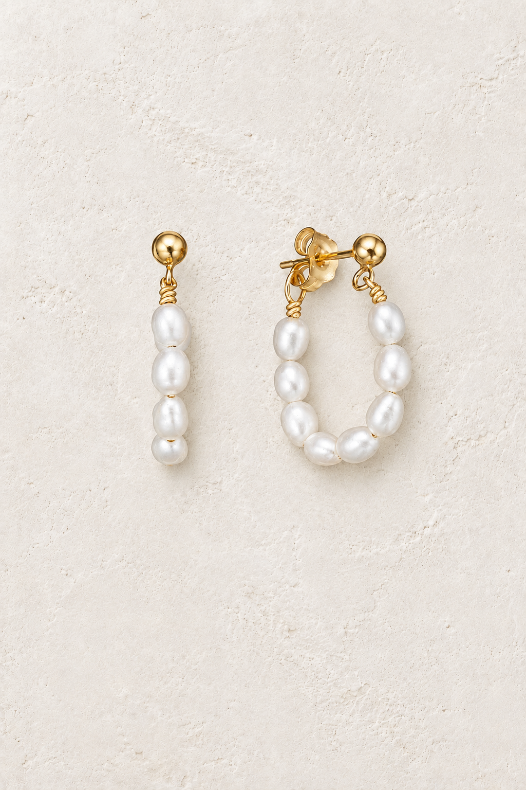 
                  
                    Gold seed pearl loop earrings on a warm off-white textured plaster background
                  
                