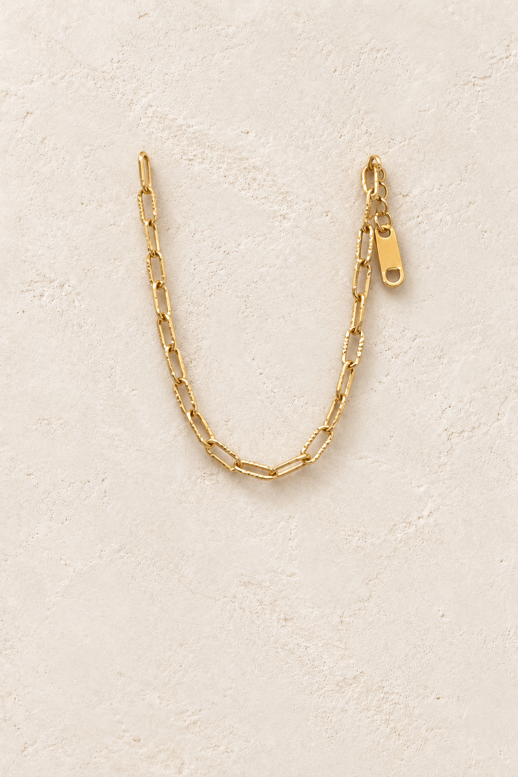 
                  
                    Gold Textured Mini Paperclip Bracelet on cream beige textured background
                  
                