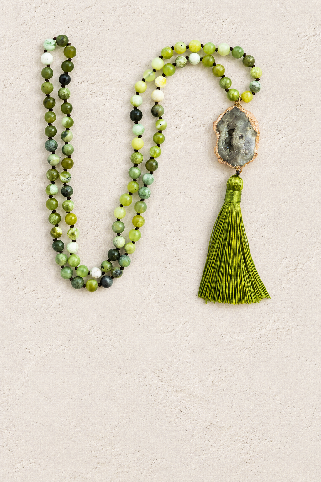 Green Agate Slice Tassel Necklace on warm ivory plaster background