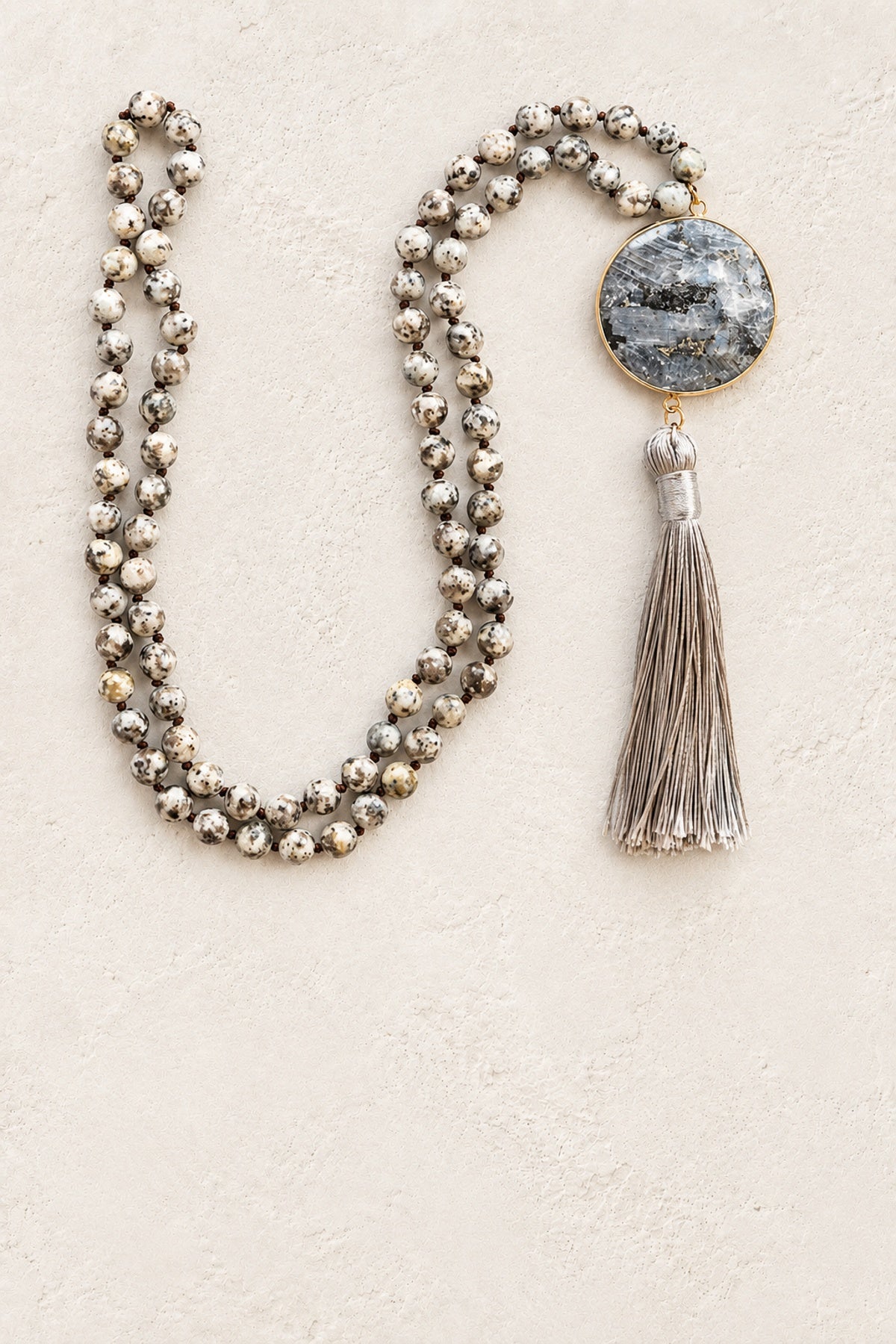 Grey Stone Tassel Necklace on warm cream plaster background