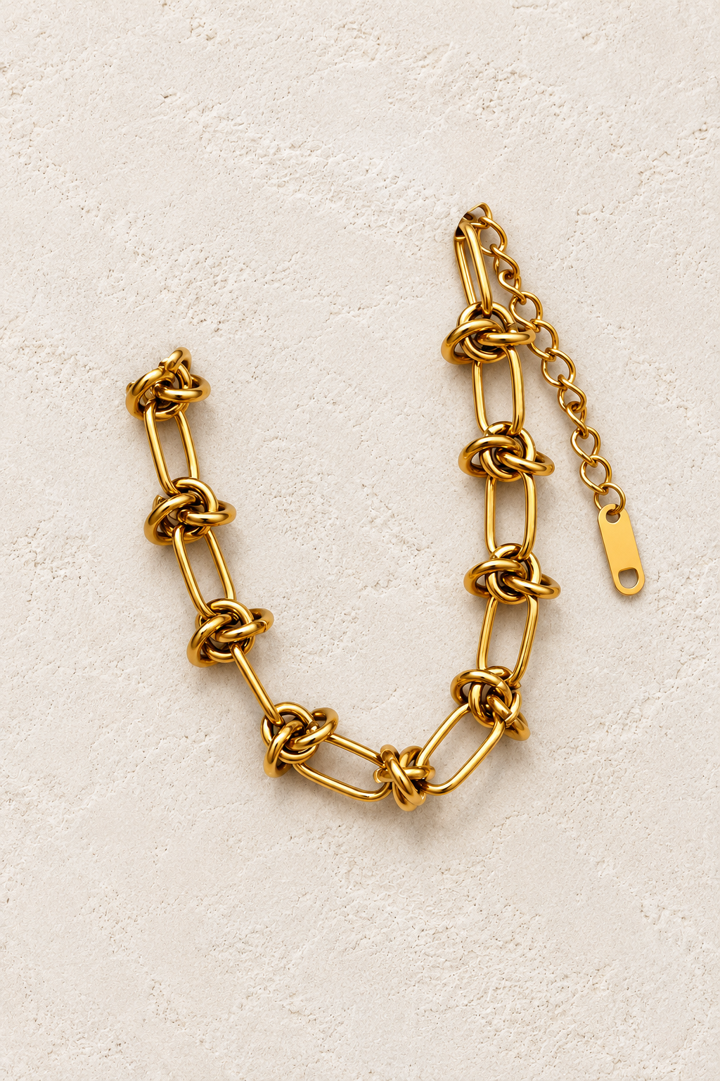 
                  
                    Imogen Gold Knot Link Bracelet on cream beige textured background
                  
                