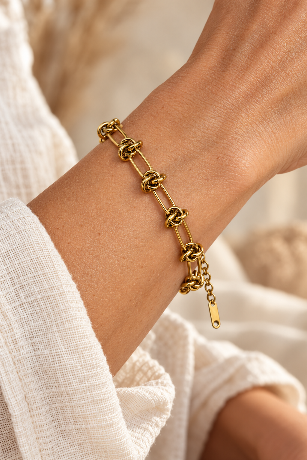 
                  
                    Imogen Gold Knot Link Bracelet worn on a model's wrist
                  
                