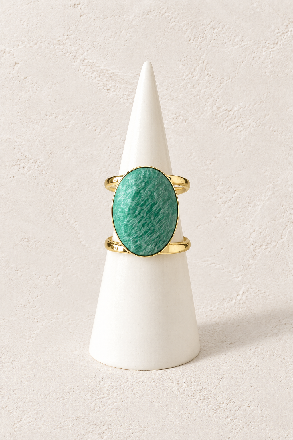 Isla Amazonite Statement Ring on a white display cone against a warm textured background