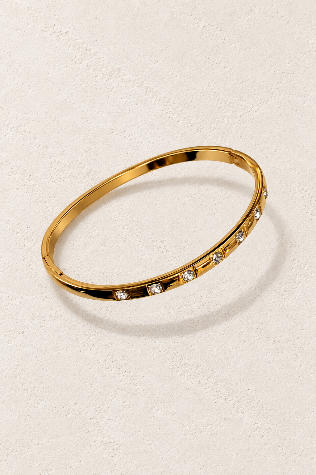 
                  
                    Liora Gold Set Crystal Bangle on cream beige textured background
                  
                