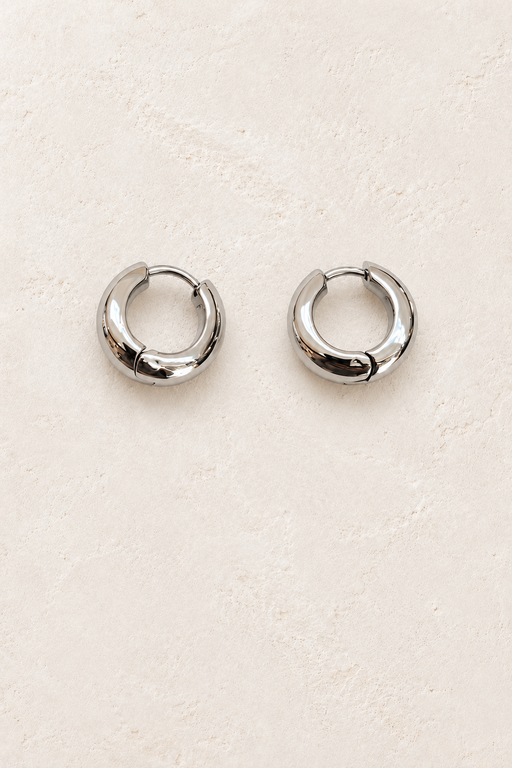 
                  
                    Maelle Silver Chunky Hoop Earrings on warm ivory plaster
                  
                