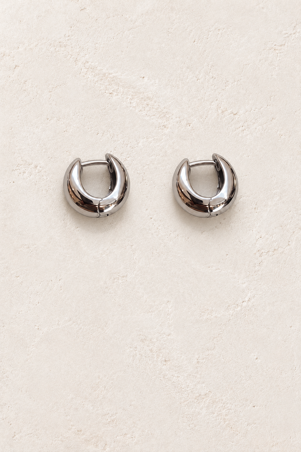 
                  
                    Maelle Silver Mini Chunky Hoop Earrings on warm ivory plaster
                  
                