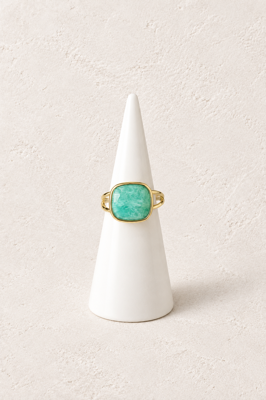 Mira Amazonite Square Ring on a white display cone against a warm textured background