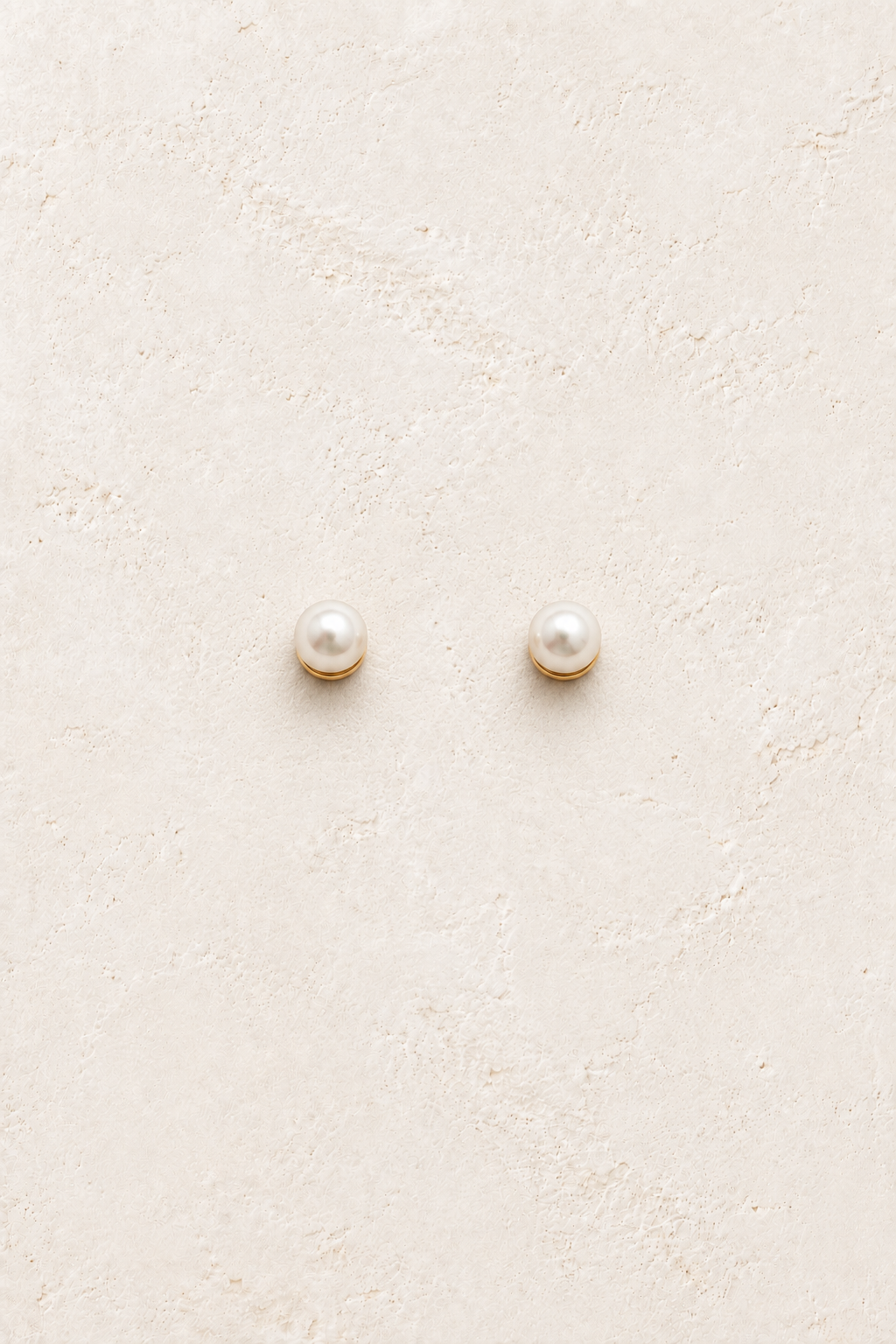 Mira Petite Pearl Studs on warm ivory textured background
