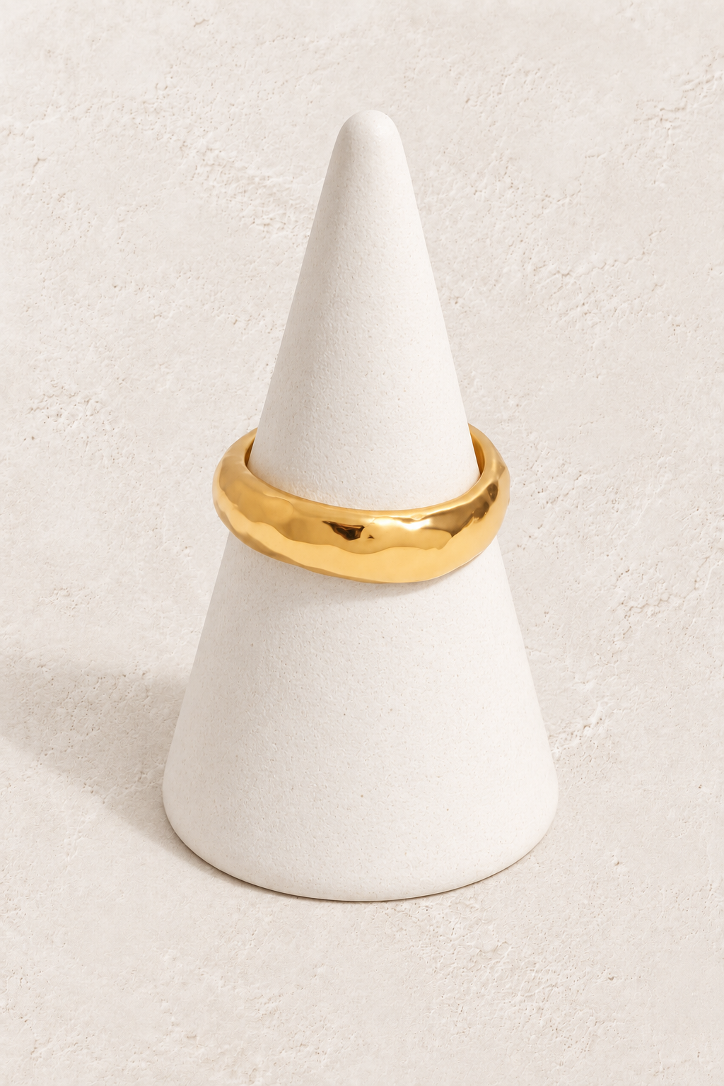 Molten Gold Band Ring Size 7 on a white display cone against a warm textured background
