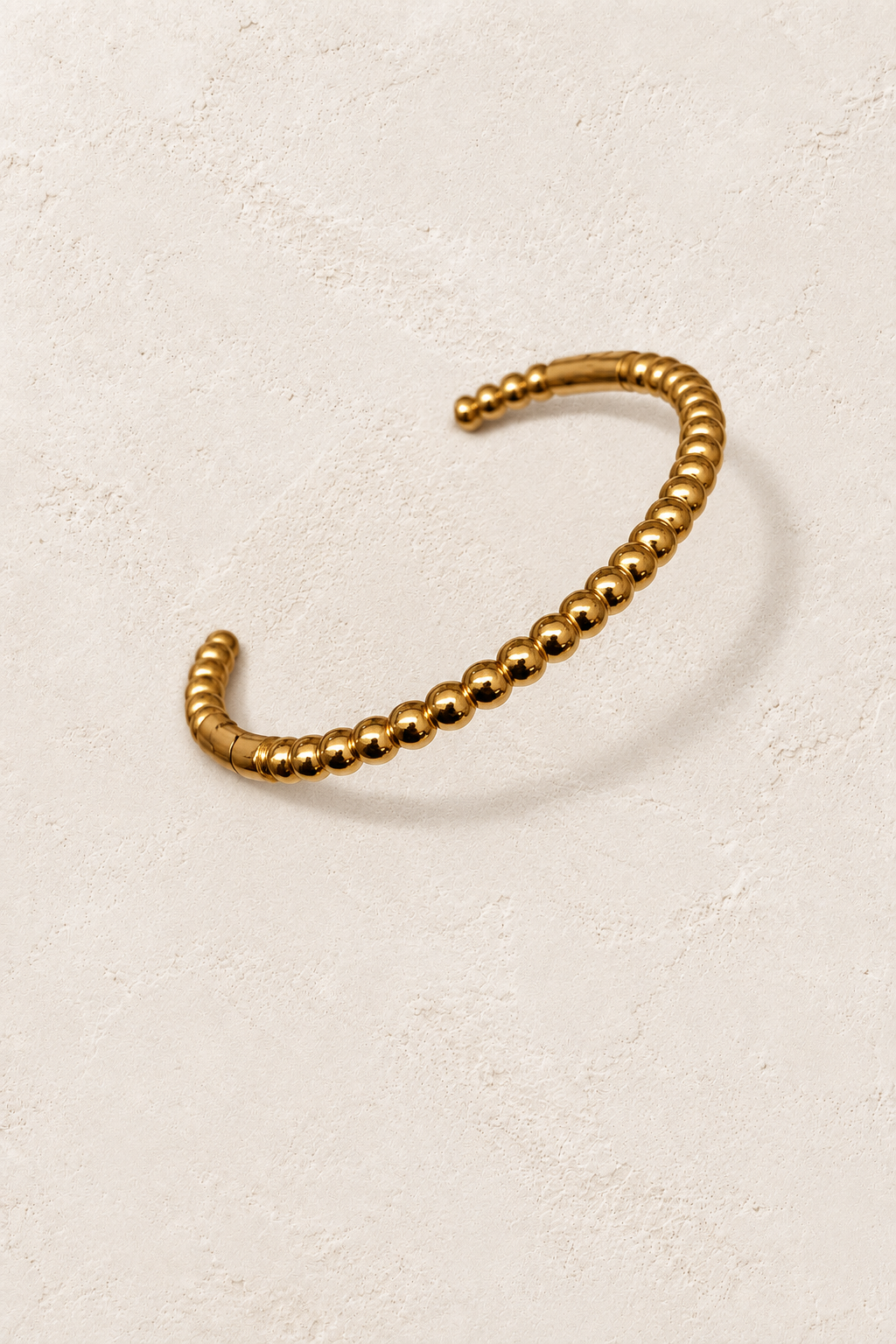 
                  
                    Naya Gold Beaded Bangle on cream beige textured background
                  
                