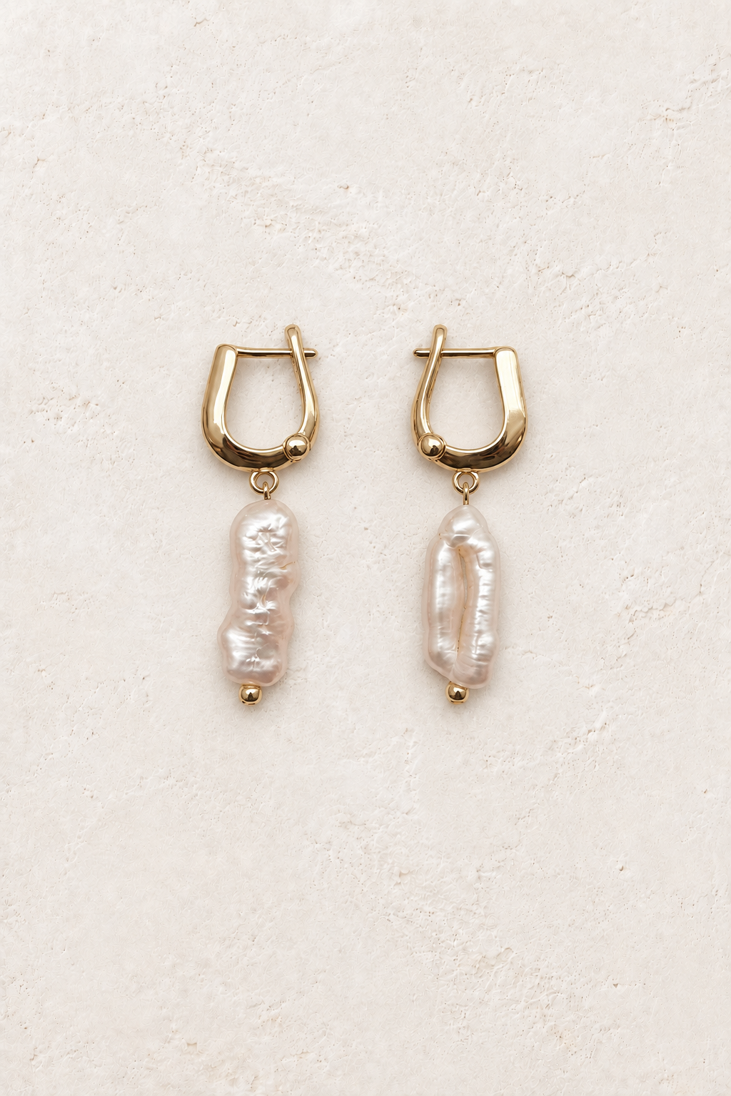 
                  
                    Nerelle Baroque Pearl Drop Earrings on warm ivory textured background
                  
                