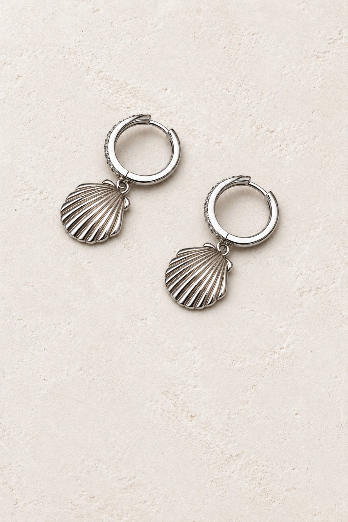 
                  
                    Nerida Silver Scallop Shell Hoop Earrings - Sterling Silver on warm ivory plaster
                  
                