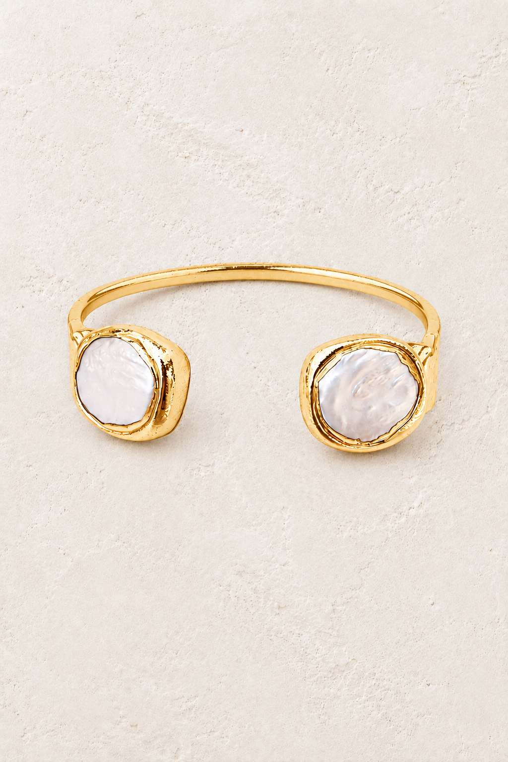 Nerina gold cuff with round freshwater pearls on a warm off-white textured plaster background