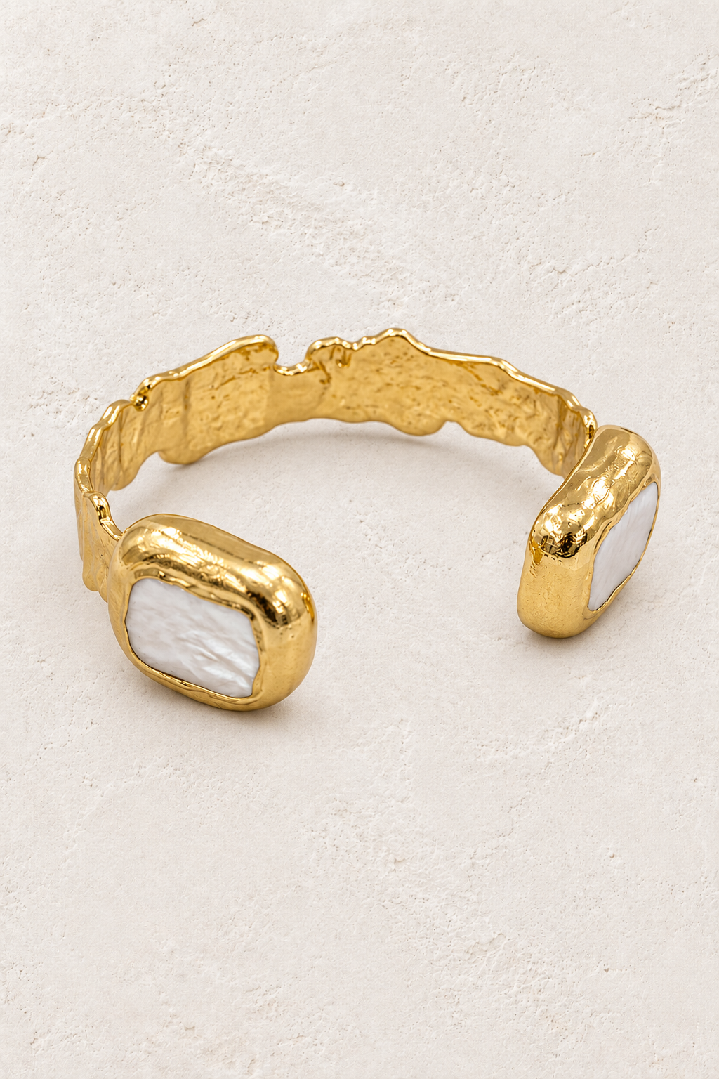 Nerina gold cuff with square freshwater pearls on a warm off-white textured plaster background