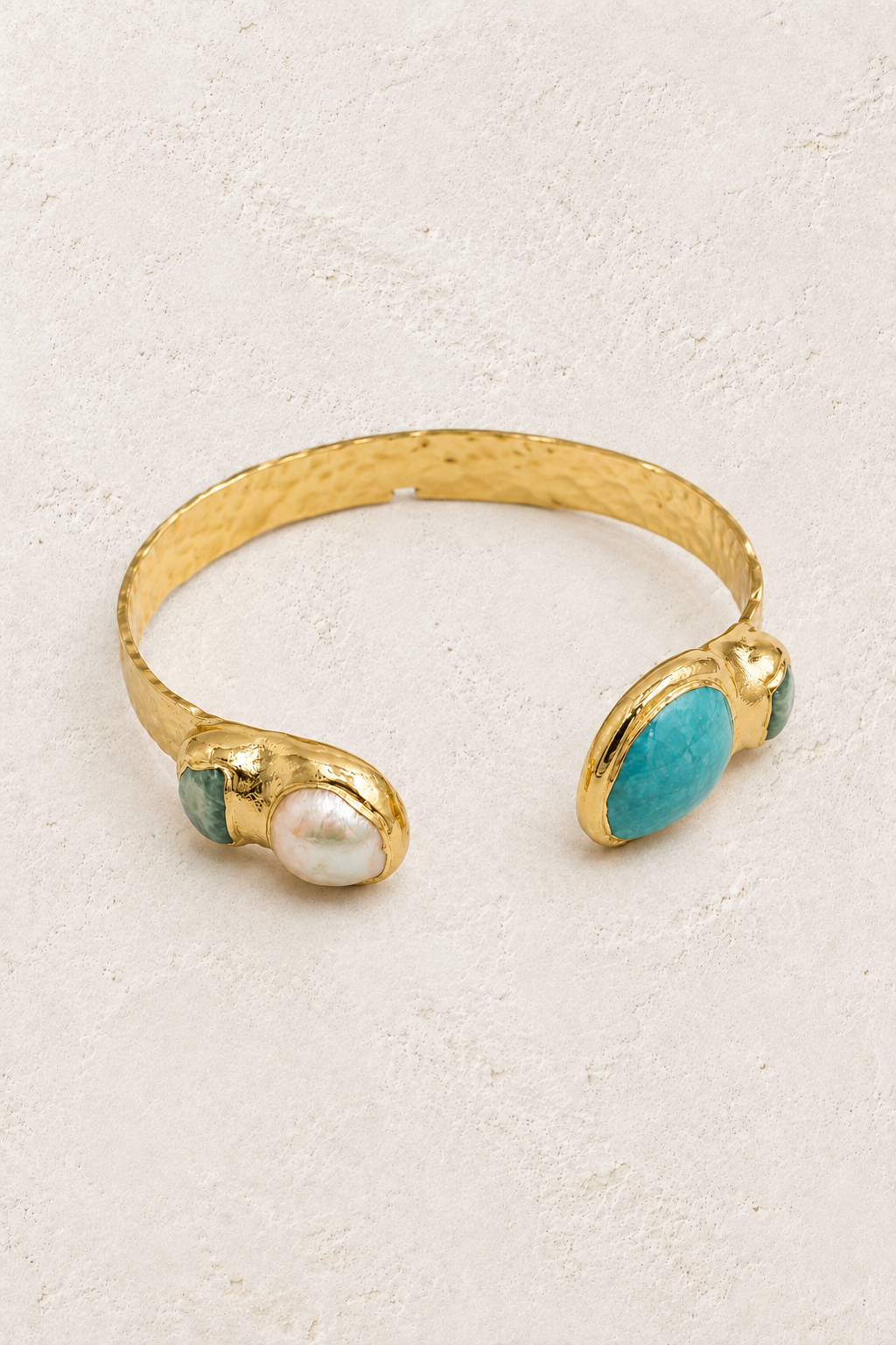 Nerissa gold cuff with amazonite and freshwater pearl on a warm off-white textured plaster background