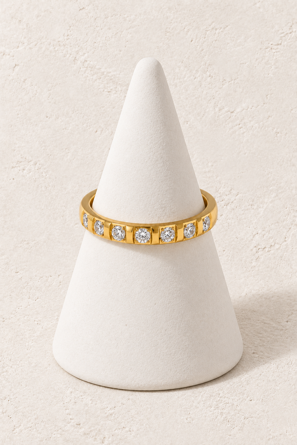 Noelle Crystal Dot Ring on a white display cone against a warm textured background
