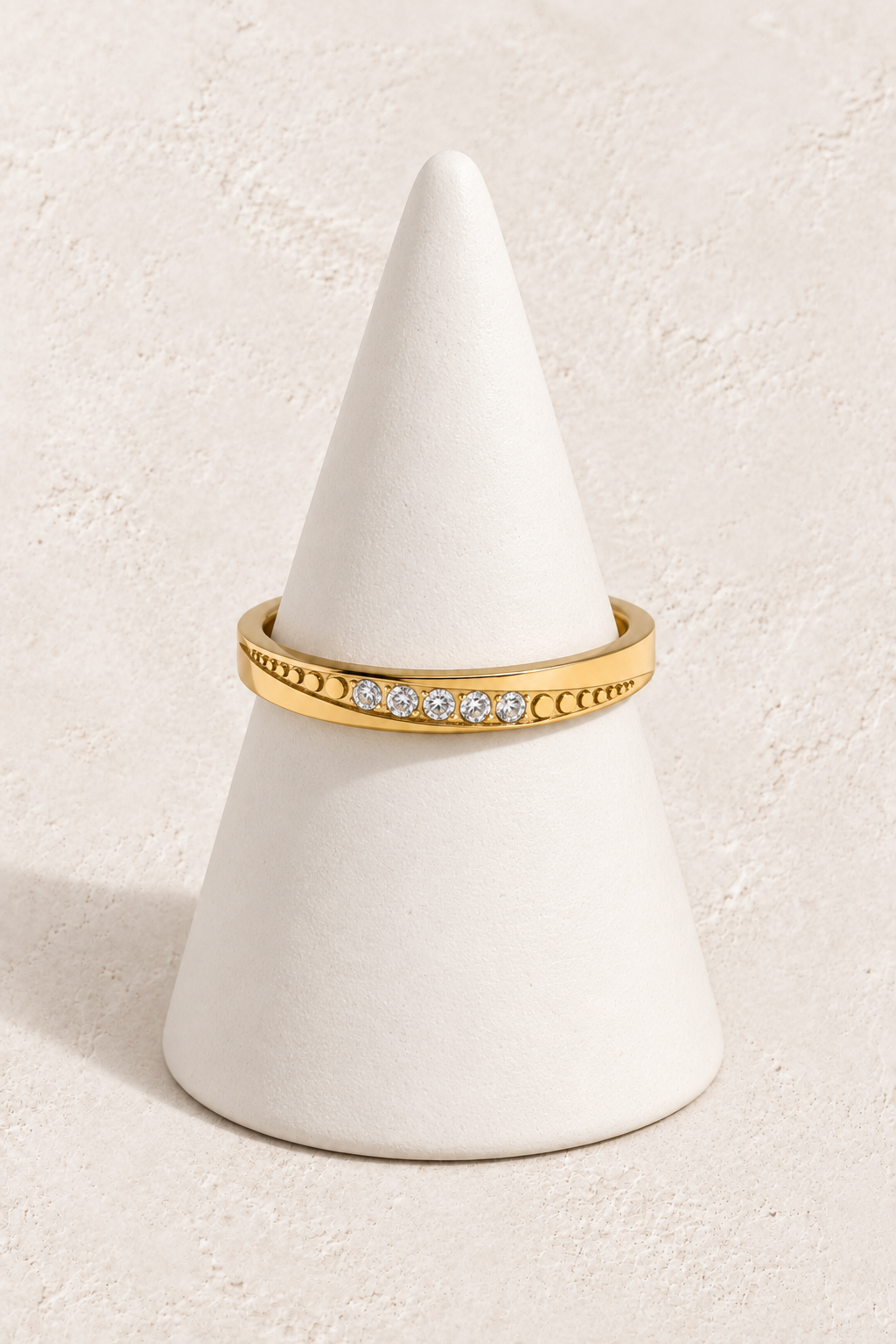 Nolani Crystal Channel Ring on a white display cone against a warm textured background