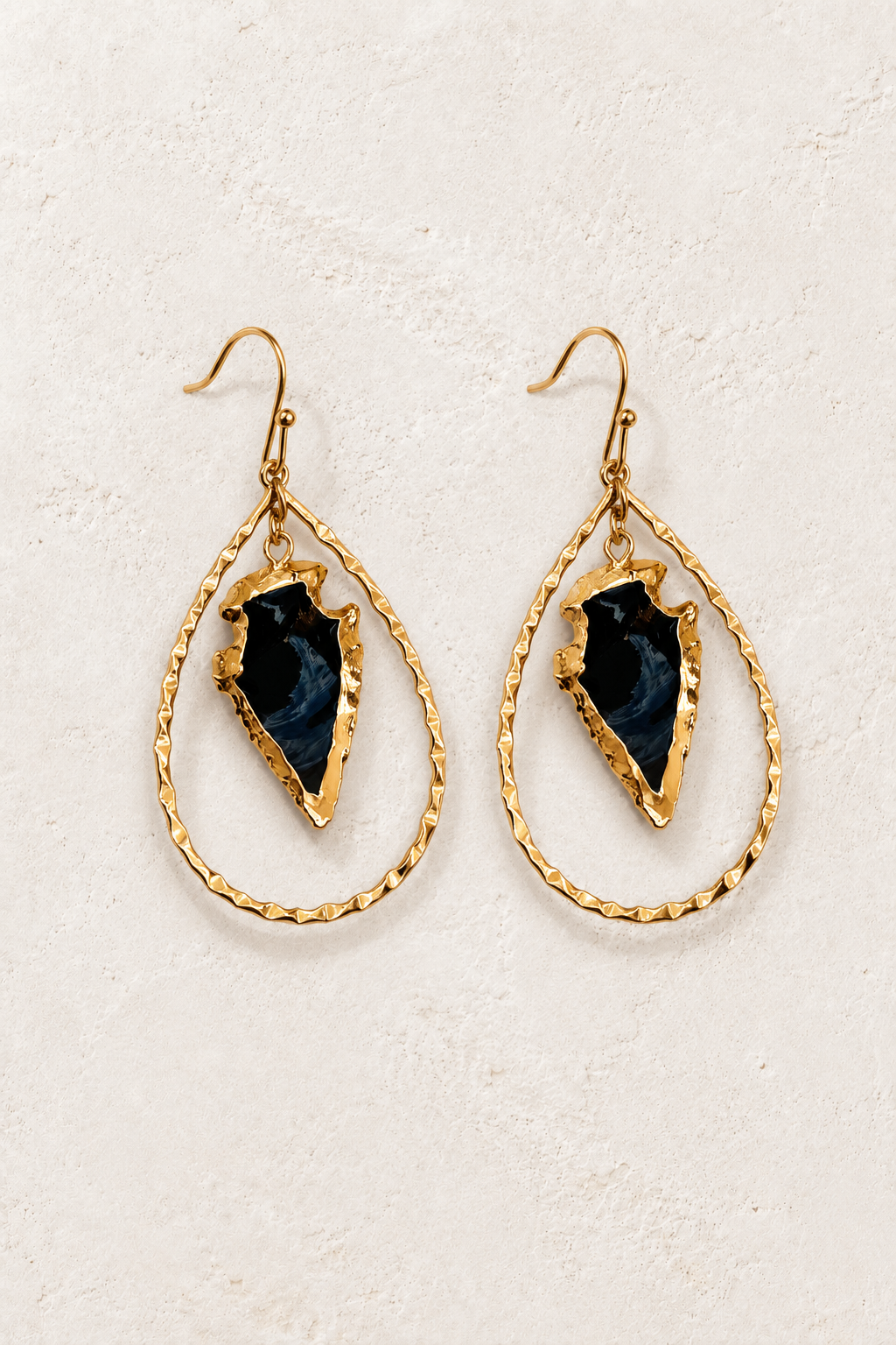 Nyra Black Arrowhead Drop Earrings on cream textured background