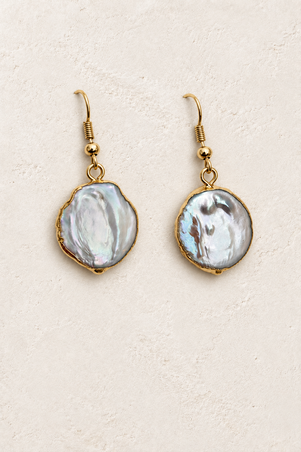 
                  
                    Oceane Gold Coin Pearl Drop Earrings on cream plaster background
                  
                