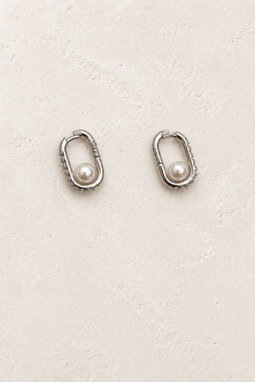 
                  
                    Odette Silver Pearl Oval Hoop Earrings on warm ivory plaster
                  
                