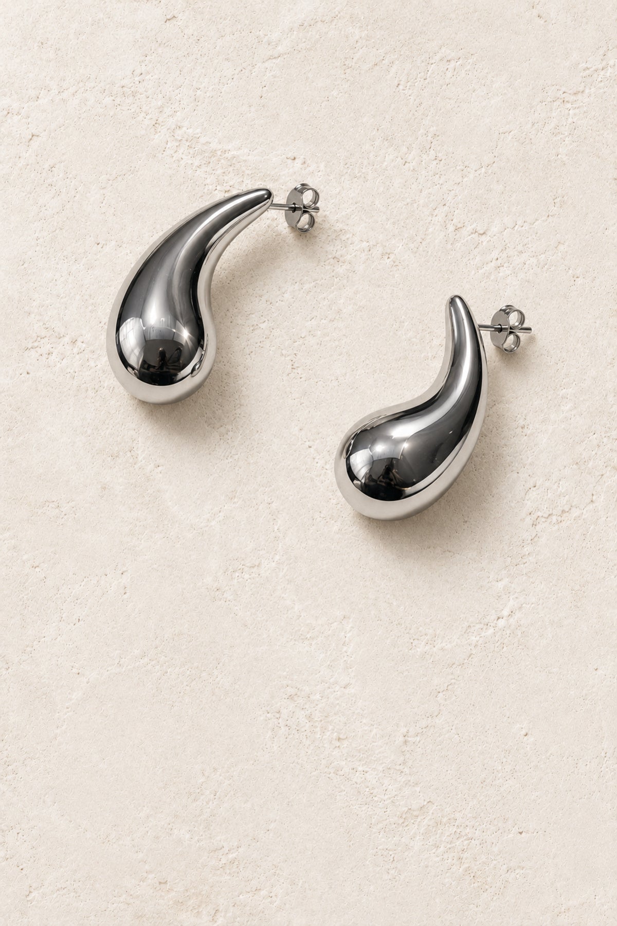 
                  
                    Oriana Silver Sculpted Teardrop Earrings on warm ivory plaster
                  
                