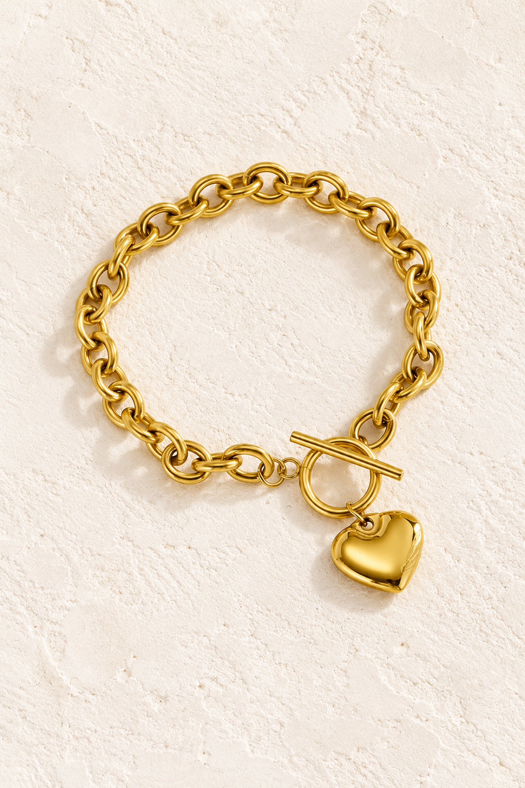 
                  
                    Gold Heart Toggle Bracelet on a beige textured background
                  
                