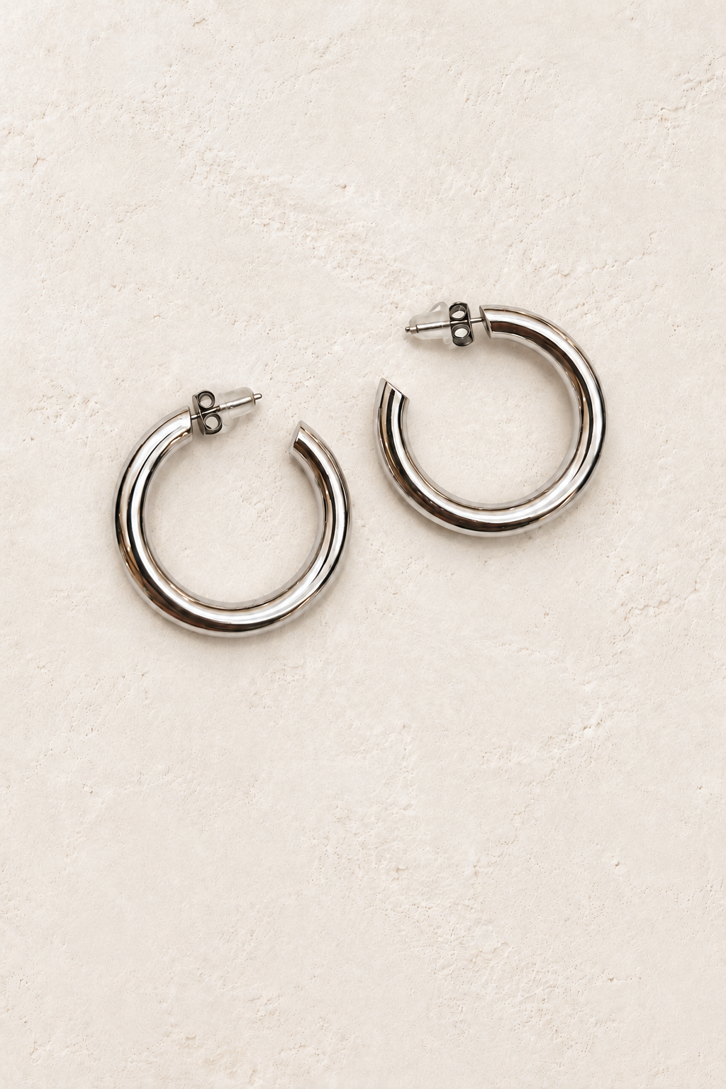 
                  
                    Orlina Silver Classic Hoop Earrings on warm ivory plaster
                  
                