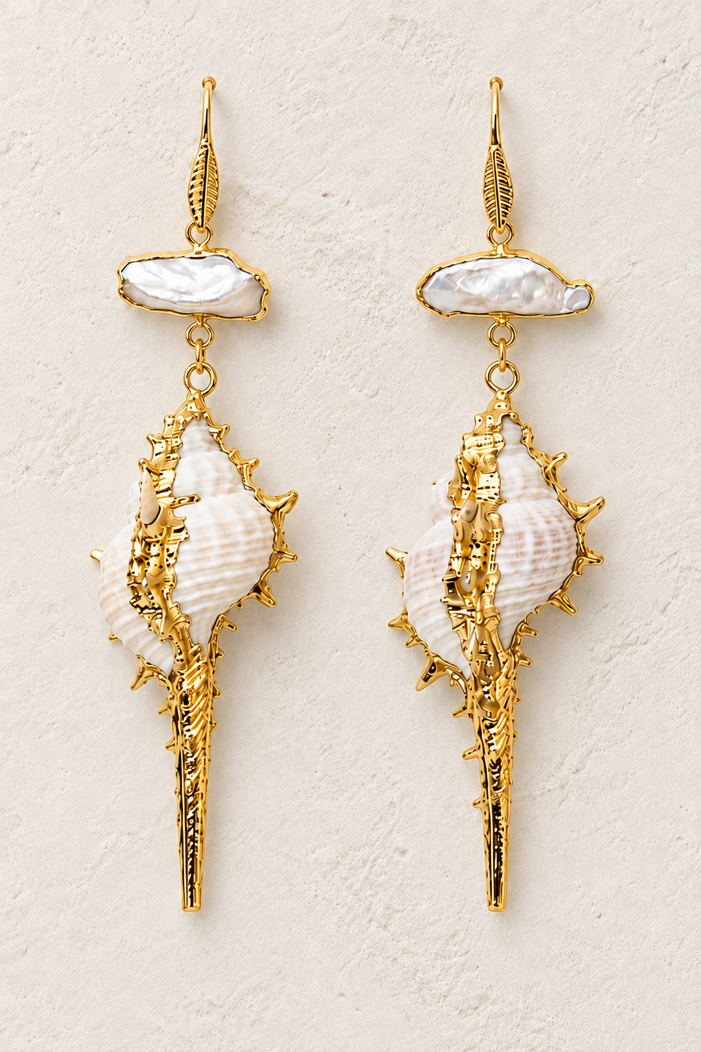 
                  
                    Pearl Conch freshwater pearl and shell drop earrings on a warm textured background
                  
                