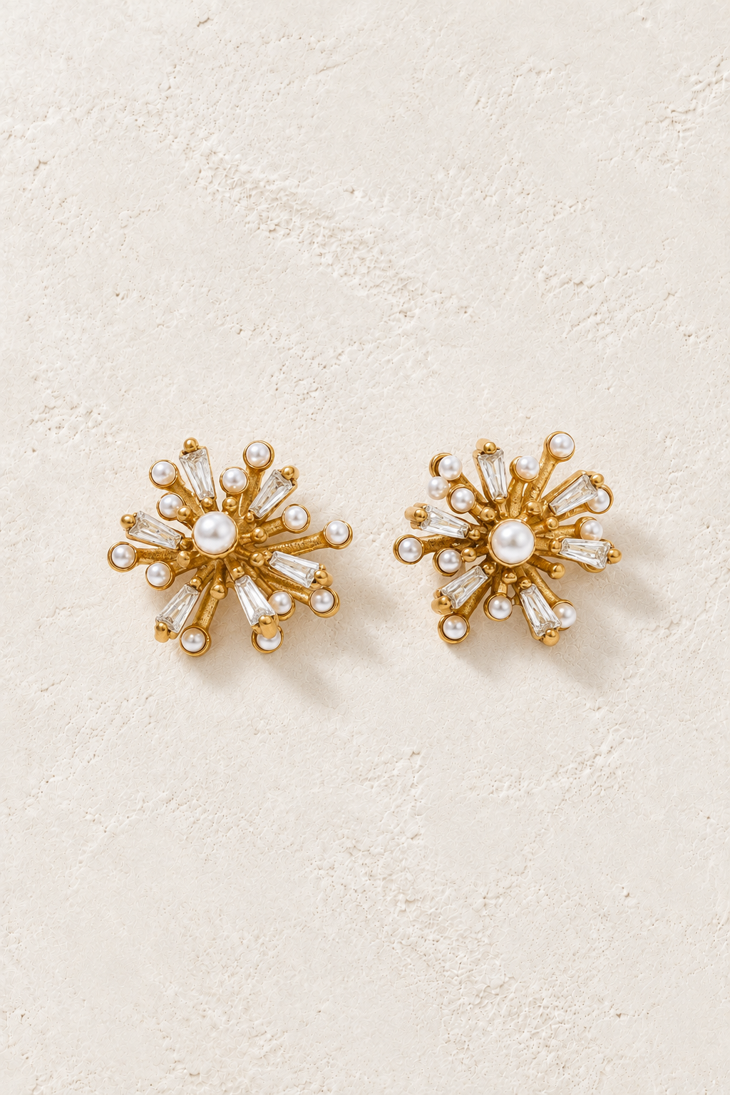 
                  
                    Gold pearl and crystal starburst stud earrings on ivory plaster
                  
                