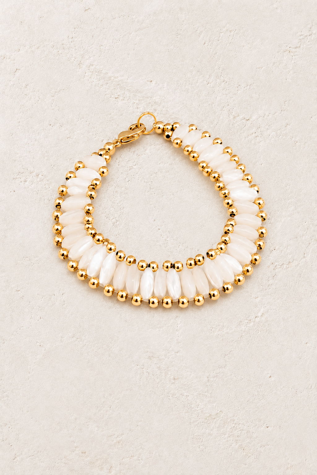 
                  
                    Pearl Glow double-strand pearl and gold bead bracelet on a warm off-white textured plaster background
                  
                
