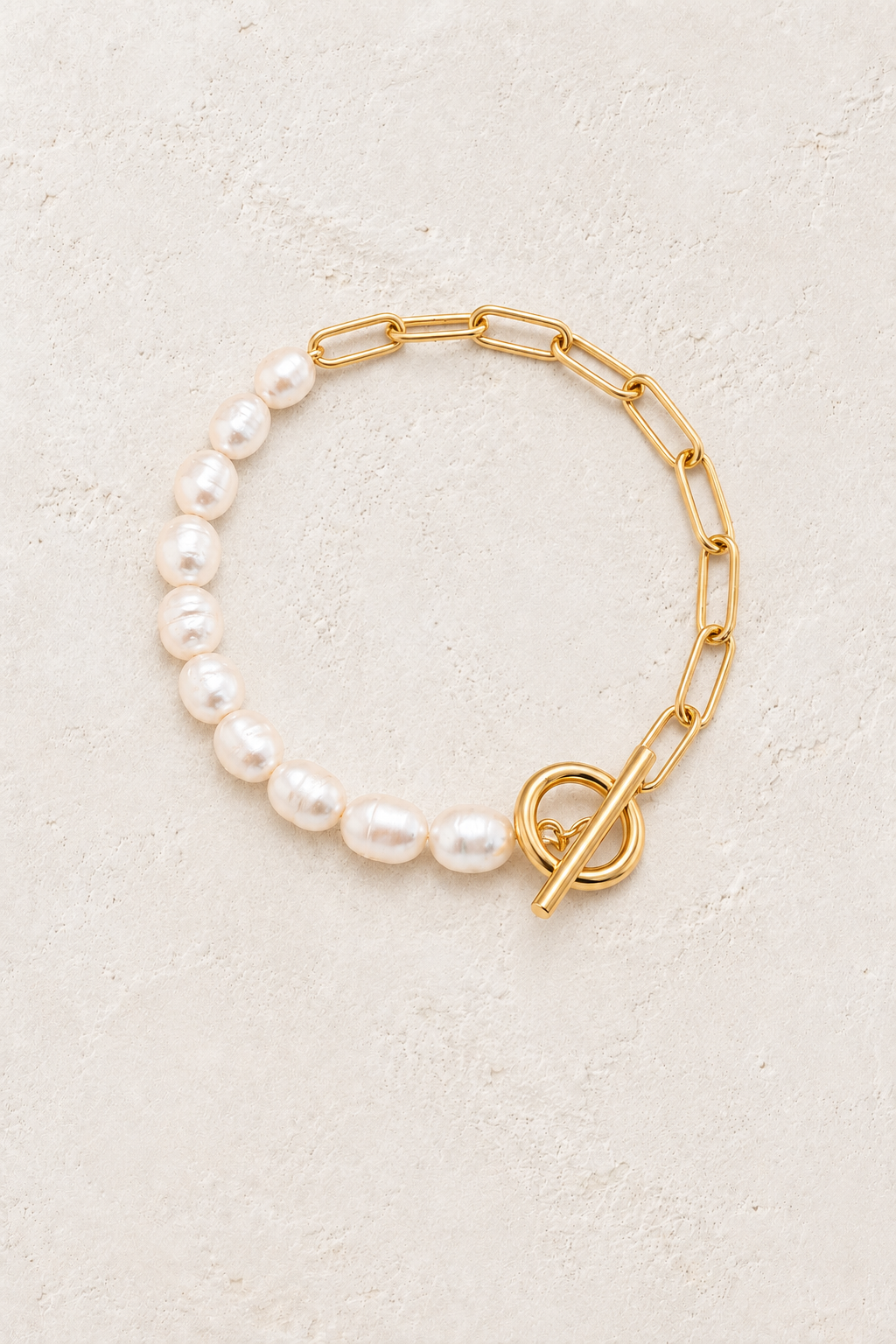 Pearl Haven freshwater pearl and gold link bracelet on a warm off-white textured plaster background