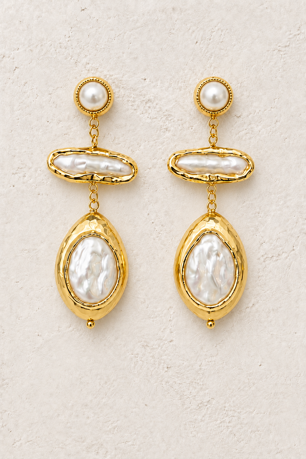 Pearl Muse freshwater pearl statement earrings on a warm off-white textured background