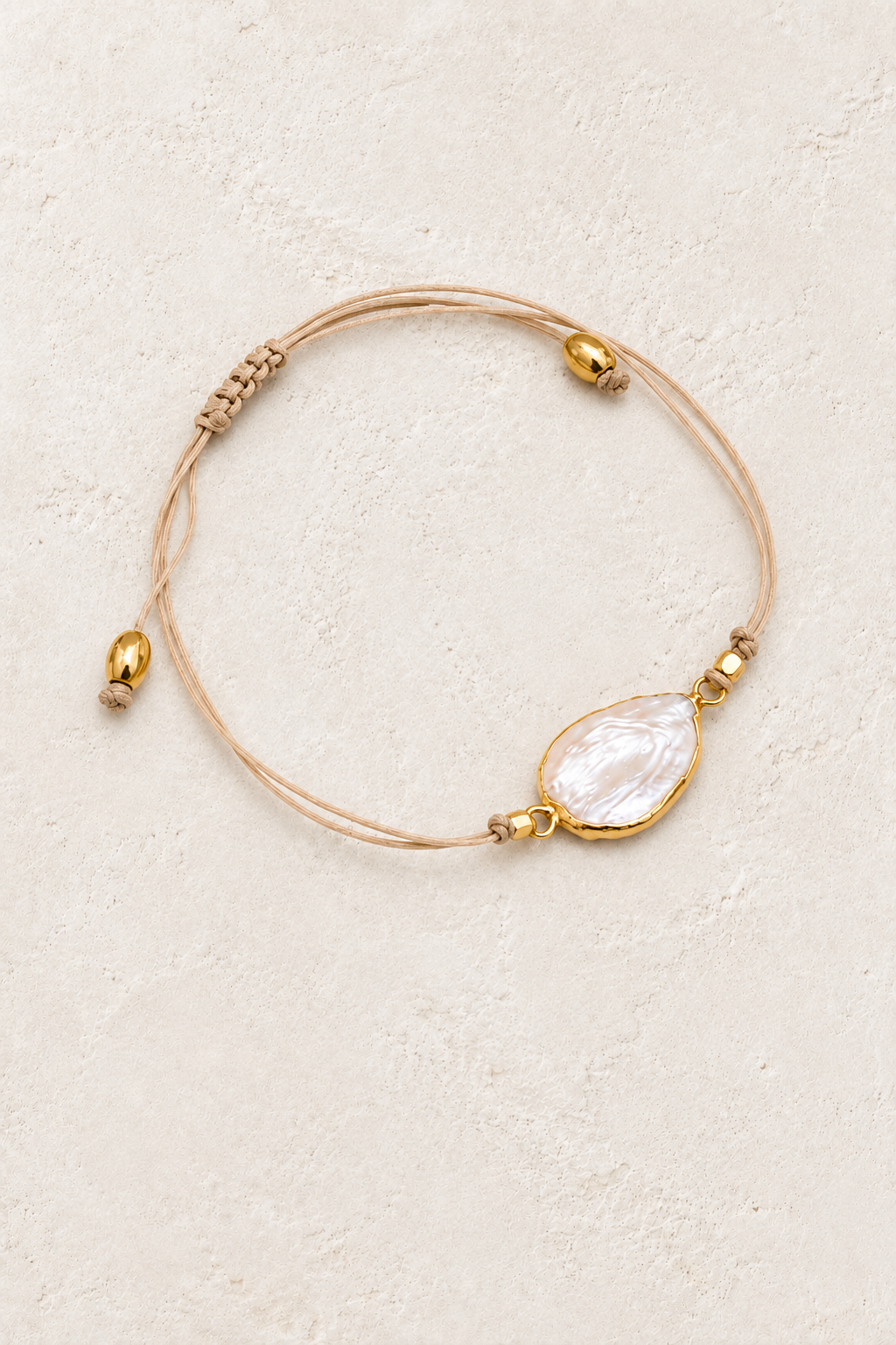 Pearl Tide cord bracelet with freshwater pearl on a warm off-white textured plaster background
