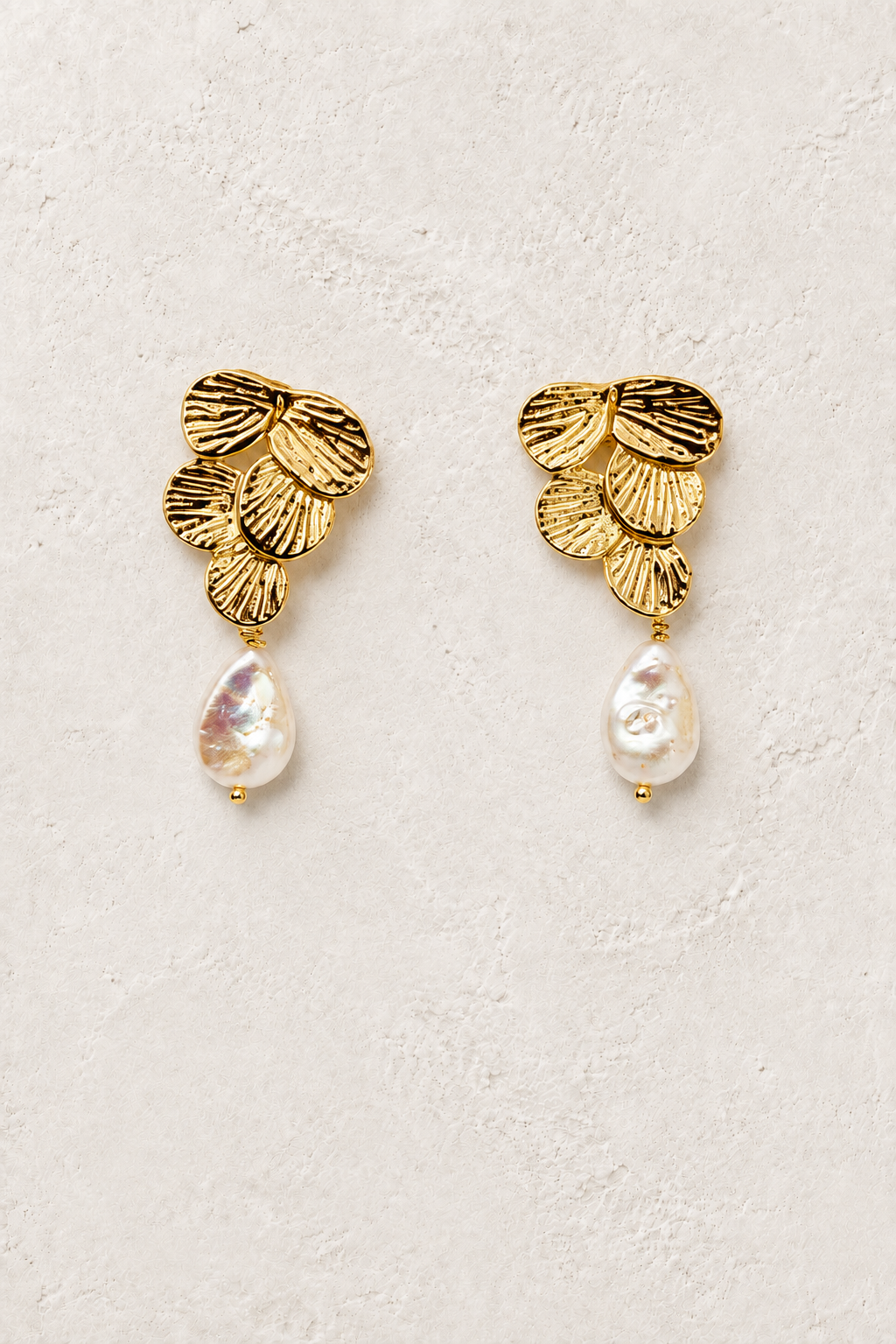 Pearla gold and freshwater pearl drop earrings on a warm textured background